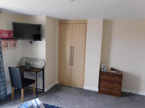 Habitación con escritorio y TV en la pared. en Double room with ensuite, tea & coffee, Falkirk, Scotland en Falkirk