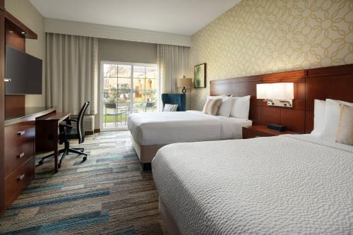 a hotel room with two beds and a desk at Courtyard by Marriott Santa Barbara Goleta in Santa Barbara