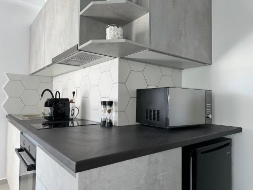 a kitchen with a black counter top with a microwave at A drop from the sea in Finikas