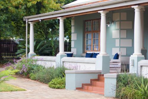 a blue house with a porch and stairs at Oude Post Guesthouse and Cottage - The Old Postmaster's House in Lydenburg