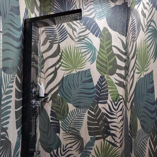 a bathroom with a shower curtain with tropical leaves at Hotel Bastide & SPA - Villa de Lourmarin in Lourmarin