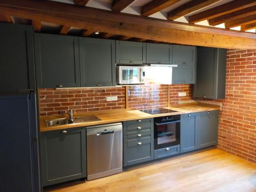 a kitchen with blue cabinets and a brick wall at Duplex avec terrasse lumineux proche vieux bassin in Honfleur