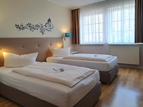 a hotel room with two beds and two windows at Hotel ELBRIVERA Alt Prester in Magdeburg