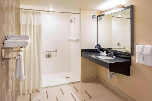 a bathroom with a shower and a sink and a mirror at Fairfield Inn & Suites by Marriott Calgary Downtown in Calgary