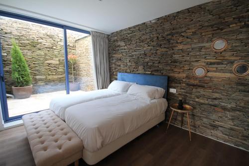 1 dormitorio con 1 cama grande y pared de ladrillo en CASAS DA FORTALEZA Casa da Muralla, en Outeiro de Rei