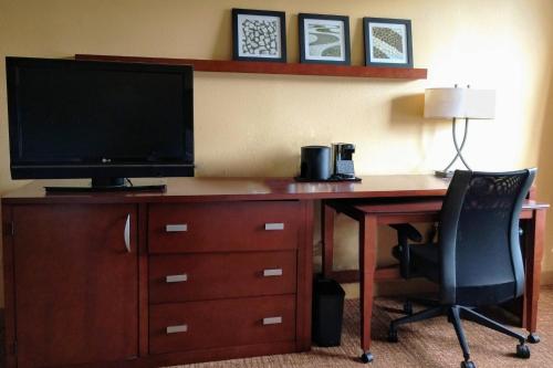 a desk with a television and a desk with a chair at Heritage Place Houston Brookhollow in Houston