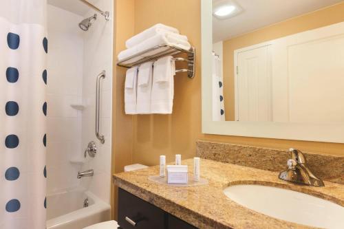 a bathroom with a sink and a tub and a mirror at TownePlace Suites Joliet South in Joliet