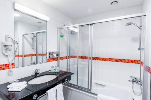 a bathroom with a glass shower and a sink at Courtyard by Marriott Pilsen in Pilsen