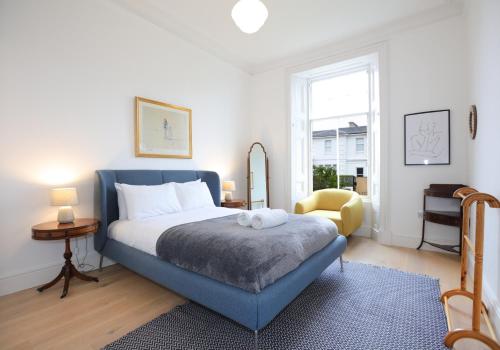 a bedroom with a blue bed and a yellow chair at Sandacres in North Berwick
