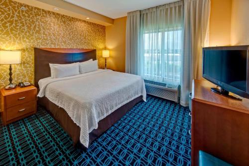 a hotel room with a bed and a flat screen tv at Fairfield Inn and Suites by Marriott Oklahoma City Airport in Oklahoma City