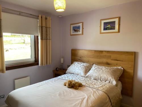 un osito de peluche sentado en una cama en un dormitorio en Creag Dubh Bed & Breakfast, en Kyle of Lochalsh