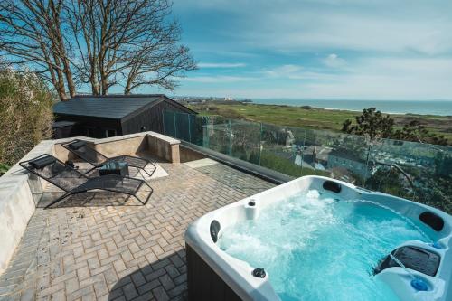 a bath tub on a patio with a view of the ocean at Priory Bay Escapes - Visum in Tenby