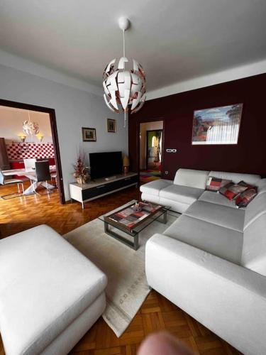 a living room with white furniture and a chandelier at Apartment Alessio - sea view in Rijeka