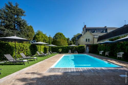 索米尔Château La Comtesse de Loire & Spa的院子里有带椅子和遮阳伞的游泳池