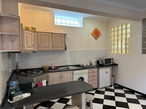 a kitchen with wooden cabinets and a checkered floor at Residência Mendonça in Faial