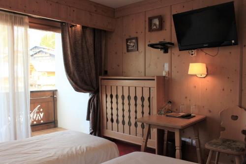a bedroom with a bed and a tv on the wall at Hôtel Macchi Restaurant & Spa in Châtel
