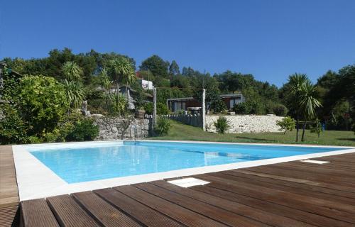 une piscine bleue avec une terrasse en bois dans l'établissement Devagar & Devagarinho, à Fafe