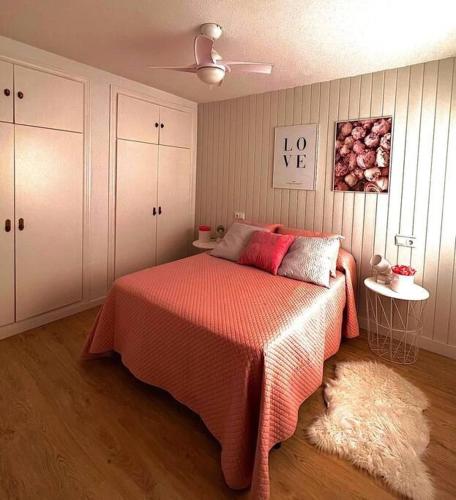a bedroom with a bed with a red blanket and a rug at Balcón al mediterráneo in Almuñécar