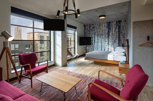 a hotel room with a bed and a couch and chairs at Moxy Minneapolis Downtown in Minneapolis