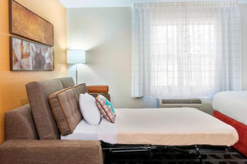 a room with a bed and a couch and a window at TownePlace Suites Savannah Midtown in Savannah