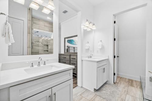 a white bathroom with two sinks and a mirror at 30A Beach House - Mira Bella in Rosemary Beach