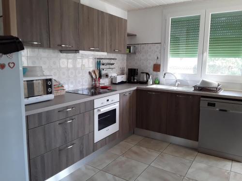 une cuisine avec des armoires marron et un four blanc dans l'établissement Chez Jo, Bages 66, Appartement 2 chambres avec terrasse, à Bages