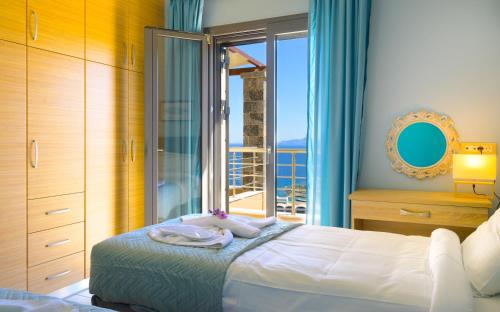 Elounda Blue Waves Residence في إيلوندا: غرفة نوم بسرير ونافذة كبيرة