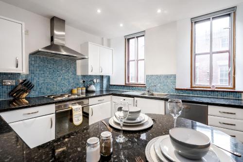 a kitchen with white cabinets and a black counter top at Lively Liverpool Living -1BR Flat Near Cavern Club - Pass The Keys in Liverpool