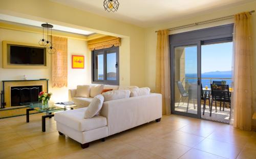 a living room with a white couch and a fireplace at Elounda Blue Waves Residence in Elounda