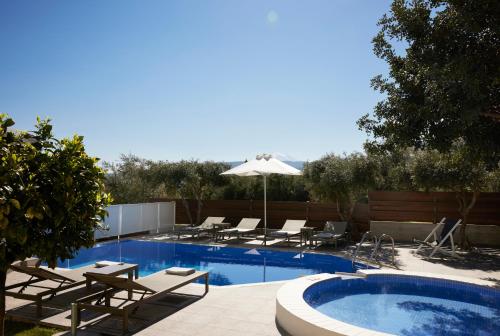 a swimming pool with lounge chairs and an umbrella at Kastellakia Executive Villa in Rethymno Town