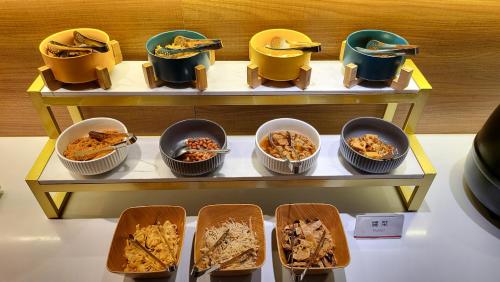 a display of food in bowls and plates on a shelf at Audi Garden Business Hotel in Taoyuan