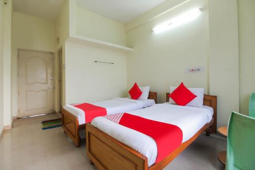 1 Schlafzimmer mit 2 Betten mit roter und weißer Bettwäsche in der Unterkunft OYO Royal Residency in Sūramangalam