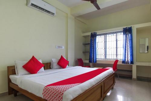 a bedroom with a large bed with red pillows at OYO Royal Residency in Sūramangalam