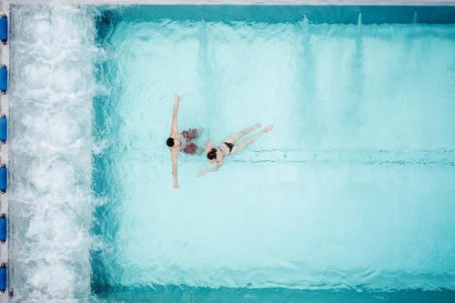 a woman is swimming in a pool in the water at Auberge de Jeunesse Saignelégier in Saignelégier