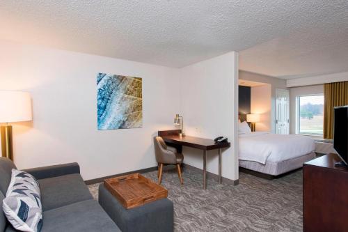 SpringHill Suites Midland في ميدلاند: غرفة في الفندق مع أريكة ومكتب وسرير