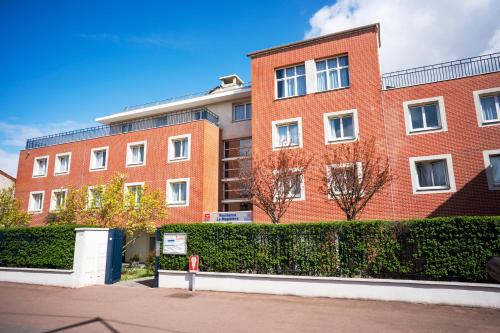 a red brick building with bushes in front of it at Séjours & Affaires Créteil Le Magistere in Créteil