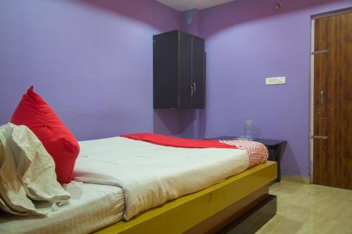OYO Smriti Guest House في Mātigara: غرفة نوم عليها سرير ومخدة حمراء