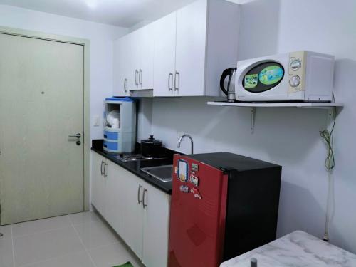 una pequeña cocina con nevera roja y microondas en JAZZ DREAM CONDOTEL WITH BALCONY AND SWIMMING POOL, en Manila