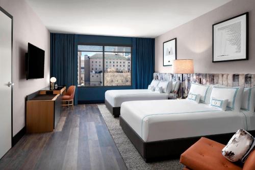 ピッツバーグにあるThe Oaklander Hotel, Autograph Collectionのベッド2台とテレビが備わるホテルルームです。