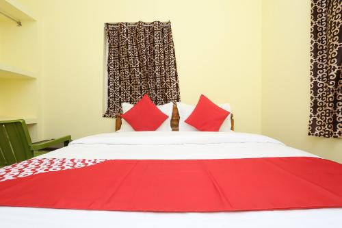 Una cama roja y blanca con almohadas rojas. en Flagship Nandan Residency, en Bārang