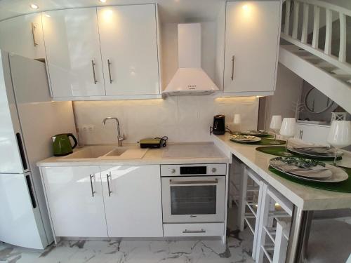 a kitchen with white cabinets and a sink at AGORA LUXURY LOFT in Ayios Nikolaos Sithonia