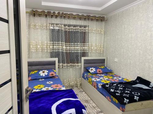 1 dormitorio con 2 camas y ventana en MehmonServis1, en Samarkand