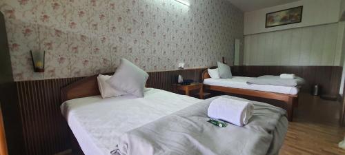 a hotel room with two beds with white sheets at Karthik Resorts, Jeolikote Nainital in Nainital