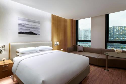 ソウルにあるコートヤード バイ マリオット ソウル ボタニック パークのベッドとソファ付きのホテルルーム