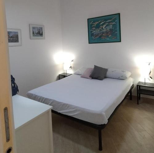 a bedroom with a large white bed with two tables at La Casina Tuttomondo in Viareggio