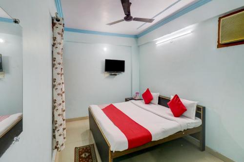 1 dormitorio con 1 cama con almohadas rojas y TV en OYO Hotel Shiv Kripa en Kānpur