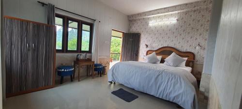 a bedroom with a bed and a desk and a window at Karthik Resorts, Jeolikote Nainital in Nainital