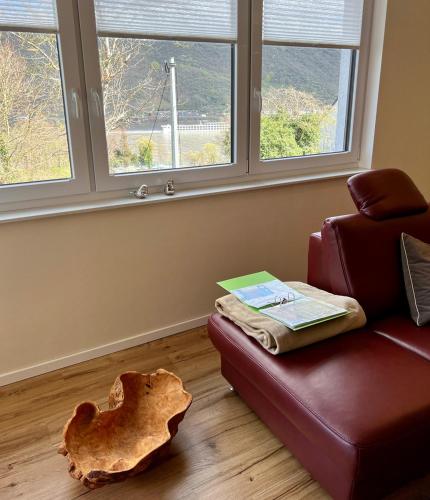 a living room with a red leather couch and windows at RheinWeinBoppard 2 - mit Rheinblick in Boppard