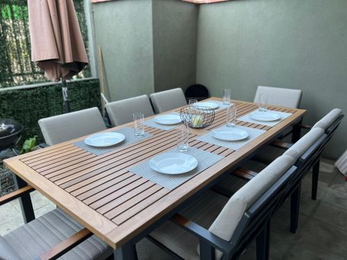 a wooden table with white plates and glasses on it at Hilton Burgas Holiday Home in Burgas City