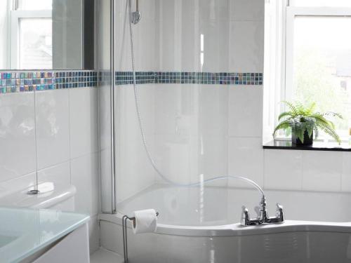 a white bathroom with a tub and a window at Garnethill Upper in Glasgow